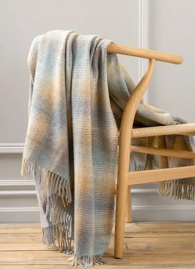 Blue and beige lambswool throw draped across wooden chair